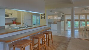A modern kitchen with a wooden bar stool seating area, a microwave, and a refrigerator. - Cape Haus Extra (Port St. Joe)