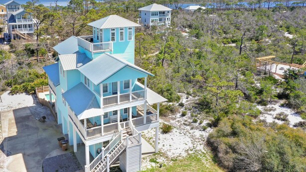 Une maison située sur la côte, à plusieurs niveaux, avec un balcon et une vue sur la plage et l’océan.