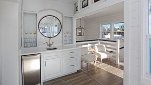 Una cocina moderna con armarios blancos, un refrigerador de acero inoxidable y un espejo redondo grande.