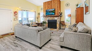A living room with a fireplace, two sofas, and a television mounted above it. - Coastal Sunshine (Port St. Joe)