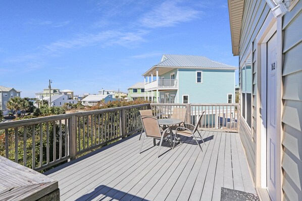 A wooden deck with outdoor furniture, a railing, and a view of neighboring houses.