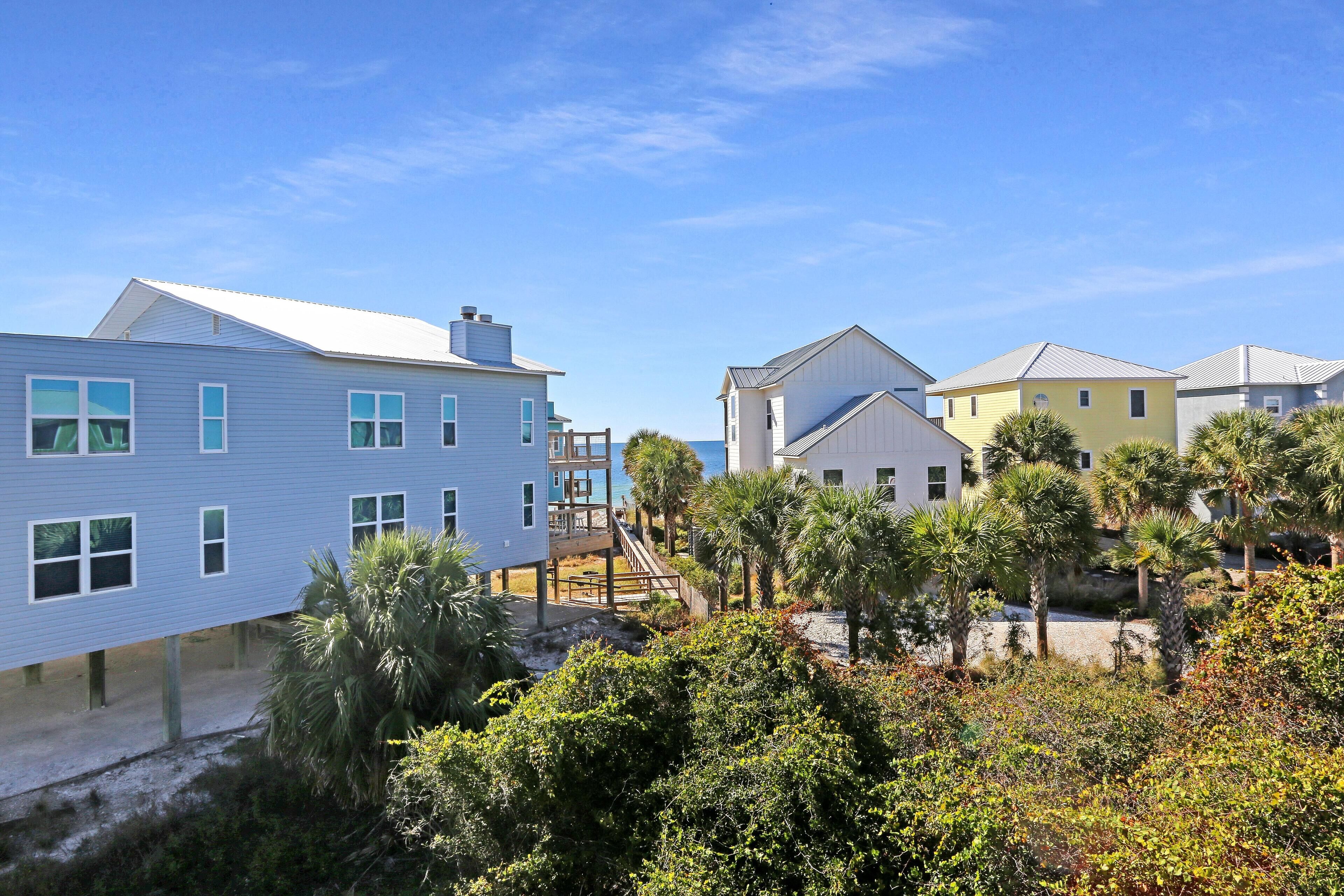 Zona residencial costera con casas modernas, una terraza de madera y abundante vegetación.