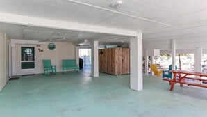 A spacious indoor area with a high ceiling, a wooden partition, and several seating options including chairs and a table. - Cape Haus (Port St. Joe)