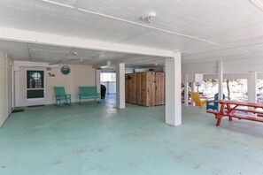 Un espacio interior amplio con techo alto, separadores de madera y varias opciones de asientos, incluyendo sillas y una mesa.