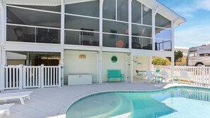 A two-story building with a swimming pool, white fences, and outdoor seating. - Cape Haus (Port St. Joe)
