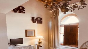 A bedroom with a bed, a TV, a lamp, and a chandelier. - Townhome (Viterbo)