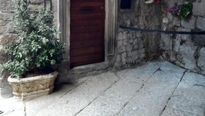 A stone building with a wooden door, a potted plant, and flower planters on the wall. - Townhome (Viterbo)