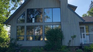 A modern two-story house with large windows, a prominent chimney, and a small porch. - Lake Life meets Country Living Near Gimli (RM of Gimli)