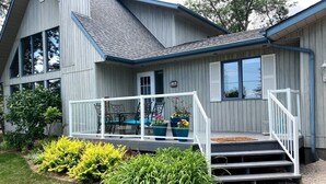 A two-story house with a covered porch, a small front yard with plants, and a visible mailbox. - Lake Life meets Country Living Near Gimli (RM of Gimli)