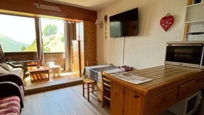 Ein gemütlicher Wohnbereich mit Esstisch aus Holz, einer Couch und einem Deckenventilator.