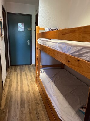 Cozy room with a bunk bed, featuring a comfortable mattress and a small shelf for storage.