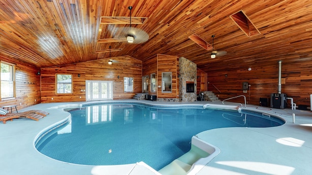 Una amplia piscina interior con paredes y techo de madera, bancos integrados y una pared de acento de piedra.