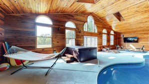 Una cabaña de madera con jacuzzi, mobiliario exterior y una hamaca.