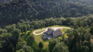 Una casa grande rodeada por un camino sinuoso y un bosque frondoso.