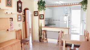 A compact living space with a dining area, kitchenette, and a small office area. - manewelacasa (torrevieja)