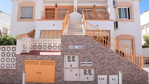 A multi-story building with a central staircase, balconies, and a garage. - manewelacasa (torrevieja)