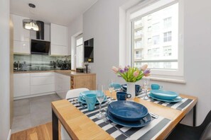 A modern kitchen with white cabinets, a black and white checkered tablecloth, and a vase of tulips.