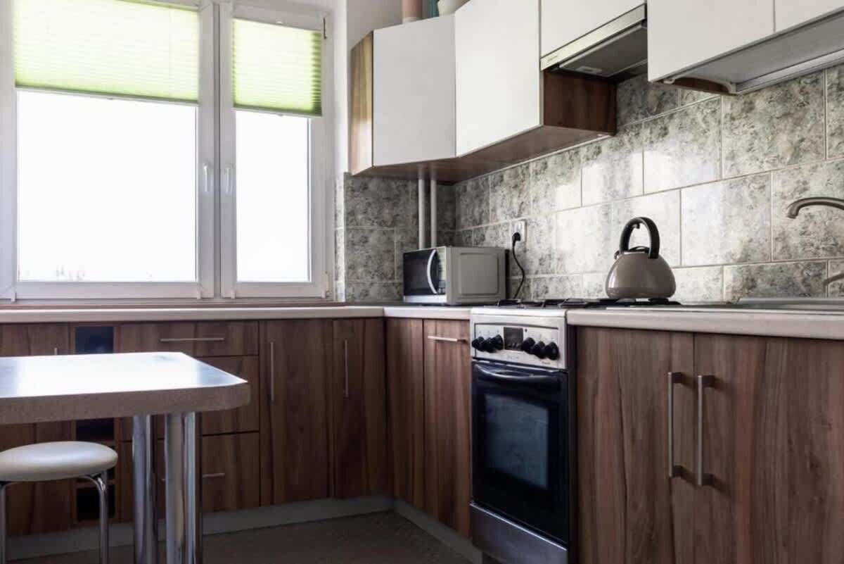 A kitchen with wooden cabinets, a microwave, an oven, and a kettle.
