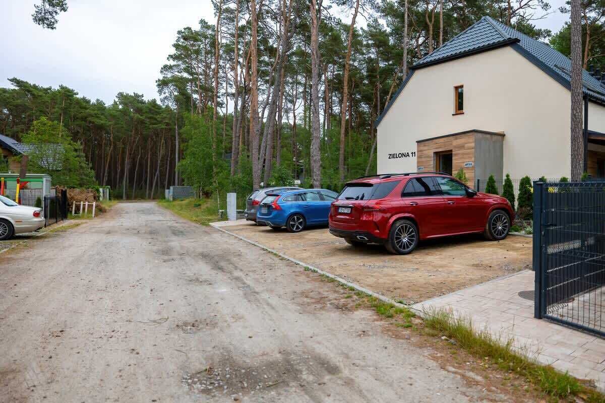 A building labeled 'ZIELONA 11' with a parking area containing two cars.