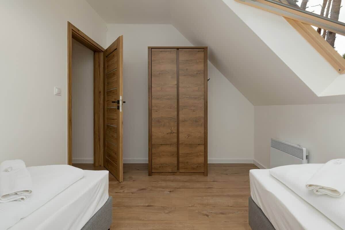 Un dormitorio con dos camas, un armario de madera y un tragaluz.