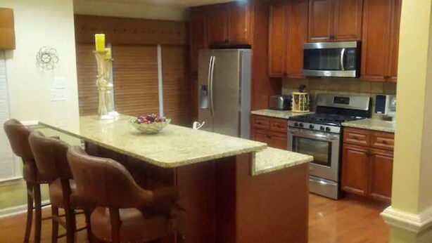 A kitchen with wooden cabinets, a stainless steel refrigerator, an oven, and a microwave. - Mini Mansion 4,100 sf NCSU/Downtown, 6br, 10 beds (Raleigh)