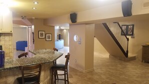 A kitchen with granite countertops, wooden chairs, a dining area, a staircase, and a living room with a blue couch. - Mini Mansion 4,100 sf NCSU/Downtown, 6br, 10 beds (Raleigh)