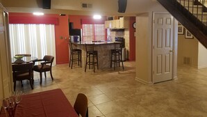 A spacious kitchen with a central island, a dining area with a red table, and a staircase leading to another level. - Mini Mansion 4,100 sf NCSU/Downtown, 6br, 10 beds (Raleigh)