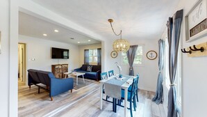 Un salon moderne comprenant un canapé, une table à manger et des chaises, un téléviseur et un lustre.