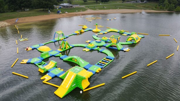 Un parc aquatique en plein air doté de diverses structures de jeux gonflables et d’une zone de plage de sable.