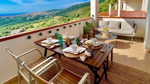 Un balcon avec une table dressée pour le petit-déjeuner, donnant sur un paysage luxuriant.