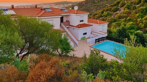 Une villa moderne dotée d’une piscine, d’un toit en terrasse et offrant une vue sur le paysage environnant.