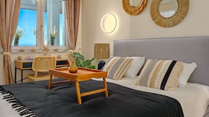 Une chambre à coucher comprenant un lit, des tables de chevet, un bureau, une chaise et deux miroirs muraux.
