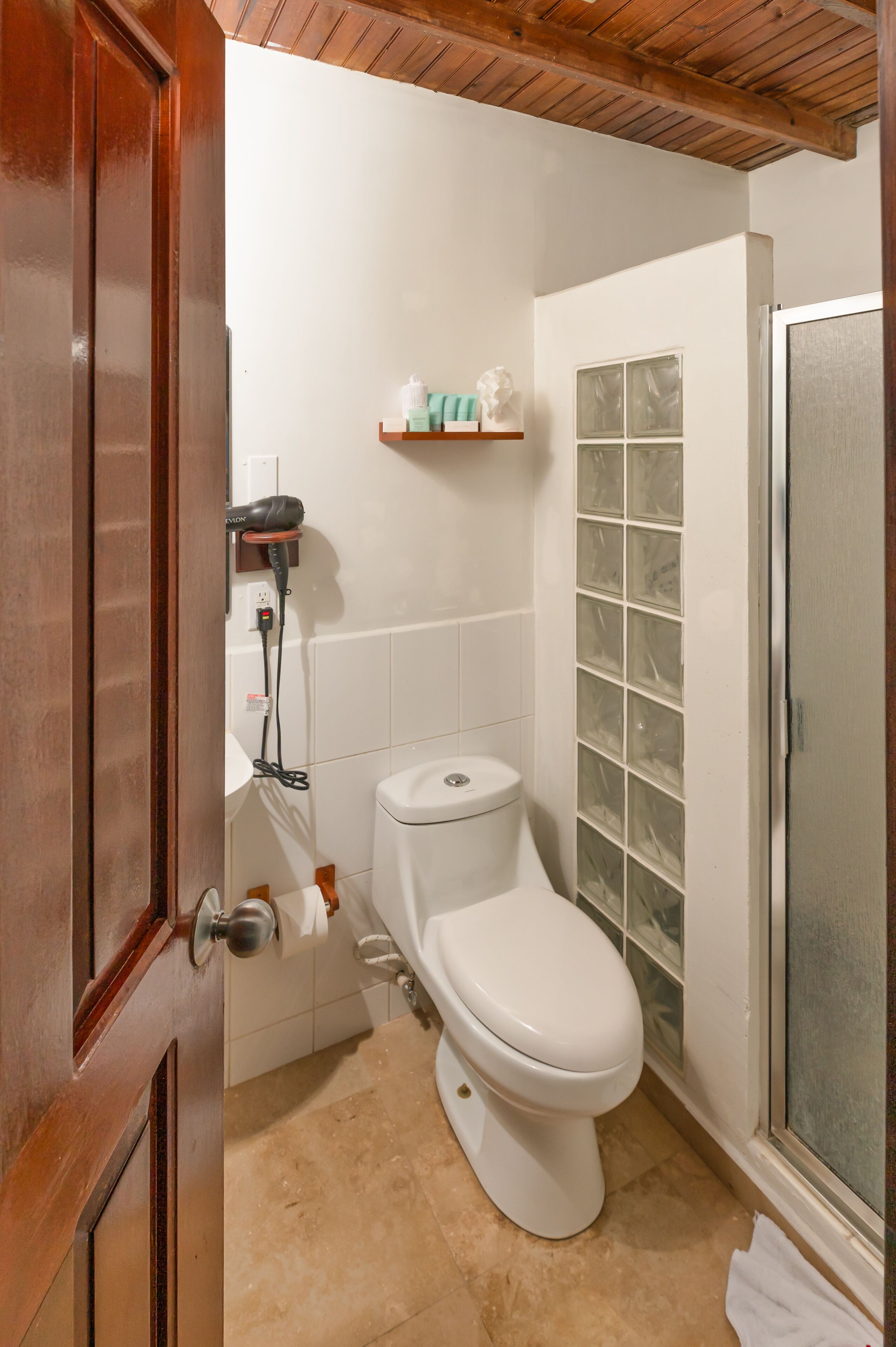 Un baño con inodoro blanco, cabina de ducha de vidrio y puerta de madera.
