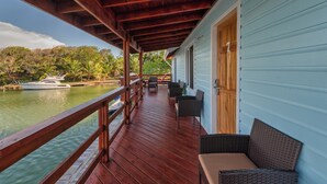 A wooden deck with outdoor furniture overlooking a body of water and greenery.