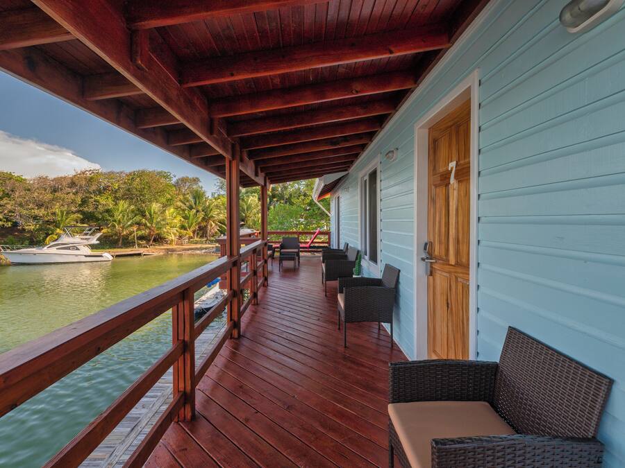 A wooden deck with outdoor furniture overlooking a body of water and greenery.