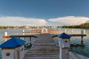A wooden pier leading to a dock with a clear view of the water and distant buildings.