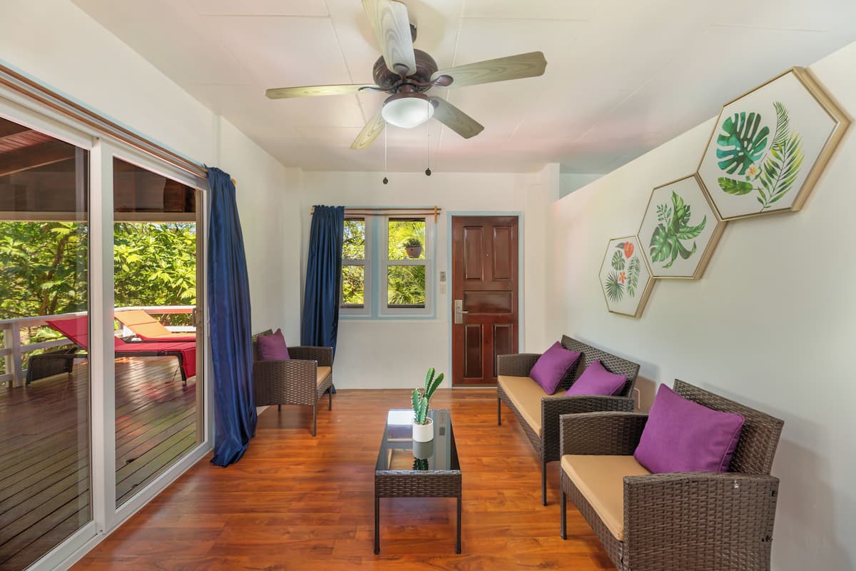 A spacious living area with a ceiling fan, wicker furniture, and a glass coffee table.