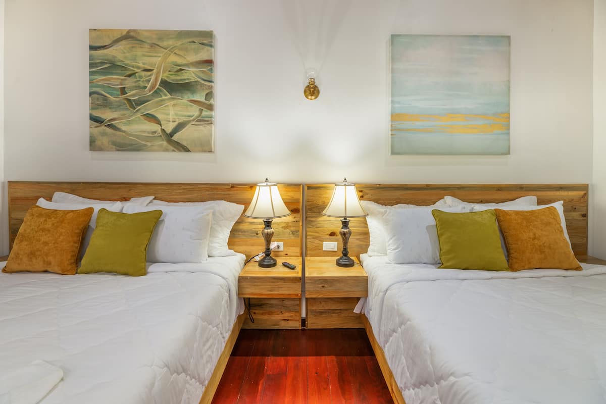A double room with two beds, wooden headboards, white bedding, and two bedside lamps.