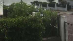 A coastal view with a building, a streetlight, and a boat on the water. - Family home with sea view (Royan)