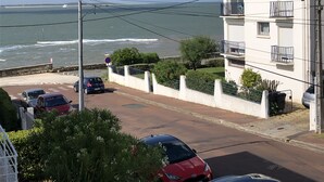 A coastal residential area with a white building, parked cars, and a view of the sea. - Family home with sea view (Royan)