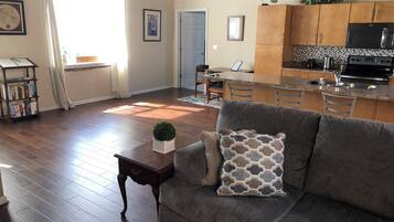 Un salon avec un canapé gris, une petite table sur laquelle est posée une plante, et une bibliothèque.
