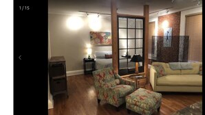 Una sala de estar con sofá, sillón, reposapiés y chimenea.