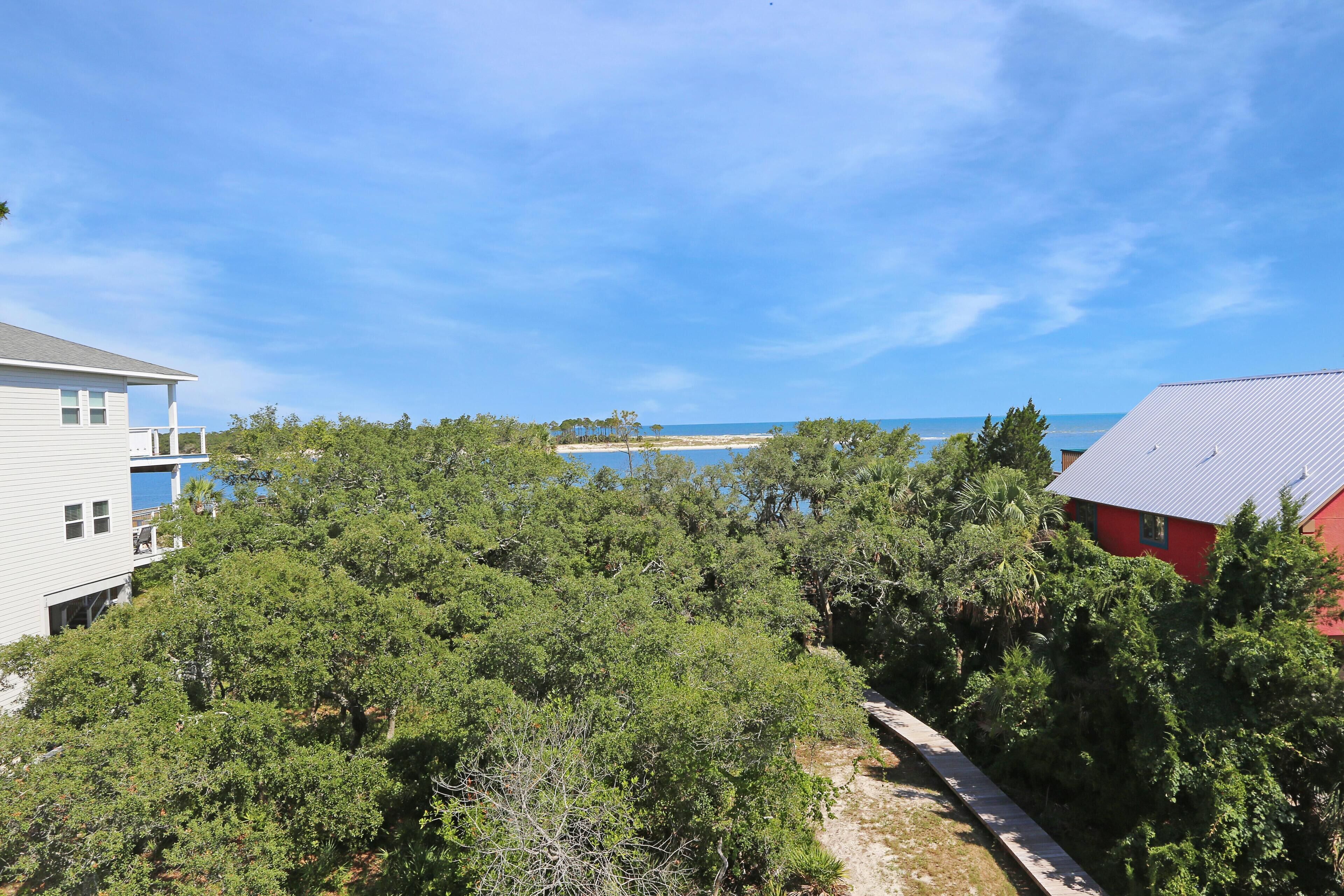 A coastal property with dense greenery, a clear view of the sea, and adjacent buildings.
