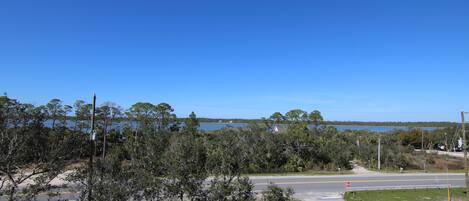 A road intersection with a stop sign, surrounded by trees and a body of water in the background.