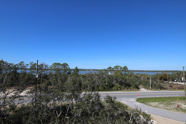 A road intersection with a stop sign, surrounded by trees and a body of water in the background.