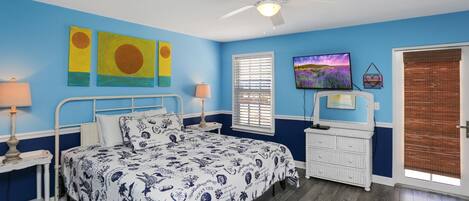 Een slaapkamer met een bed, een plafondventilator, een televisie en kunstwerken aan de muren.