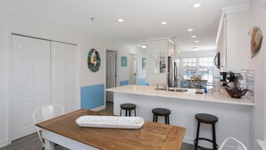 A modern kitchen with a central island, white cabinetry, and a large window providing natural light.