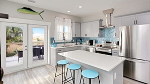 A modern kitchen with a large island, stainless steel appliances, and a view to the outside. - Hesed Beach Cottage (Port St. Joe)