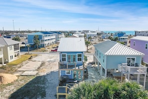 A coastal residential area with multiple two-story houses, some with balconies, and a clear view of the beach in the background. - Hesed Beach Cottage (Port St. Joe)