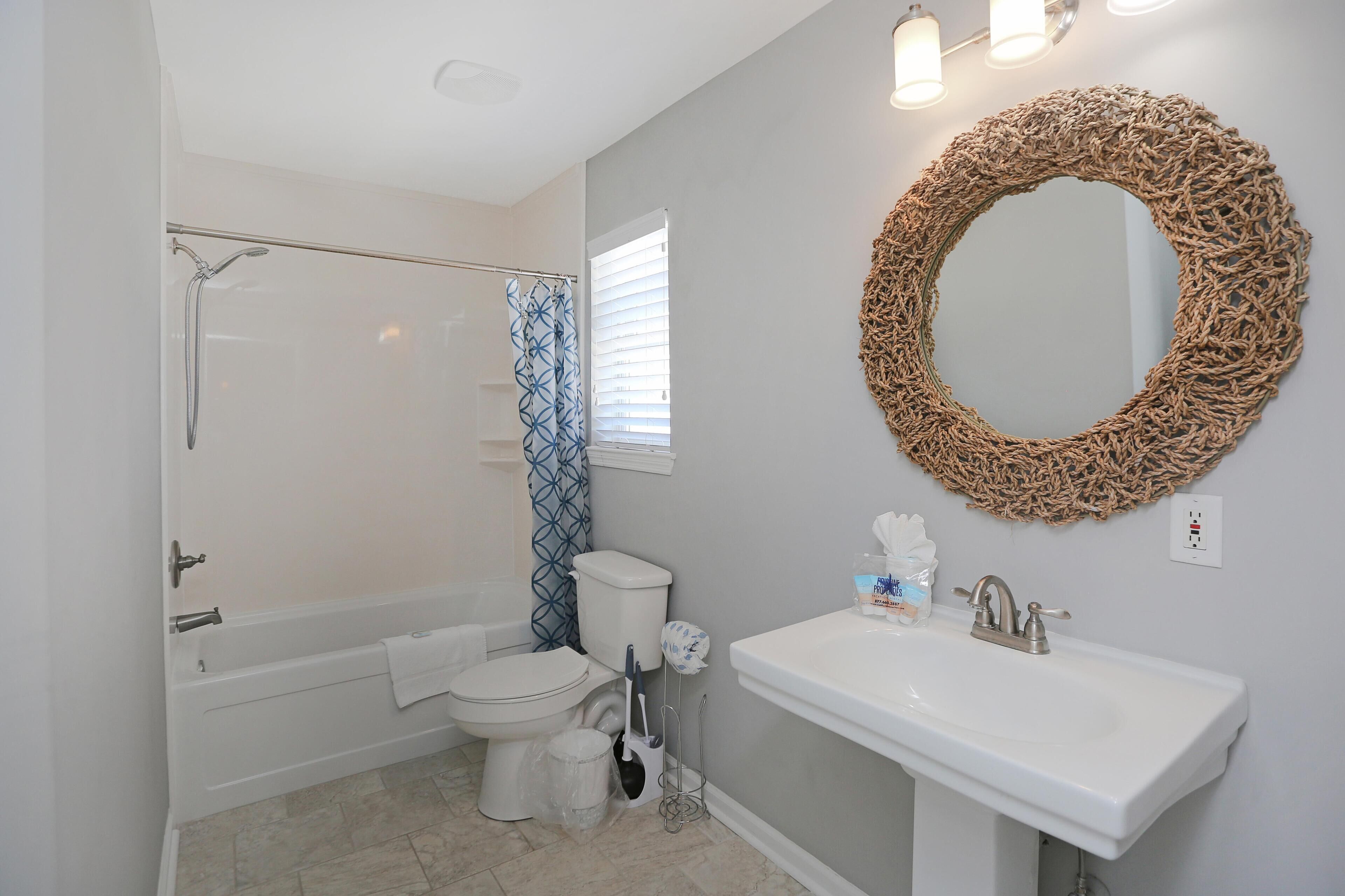 Une salle de bain équipée d’une baignoire, de toilettes, d’un lavabo et d’un miroir décoratif.